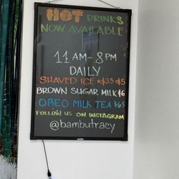 Hours - A chalkboard sign lists drink options, prices, and business hours, with colorful handwritten text.