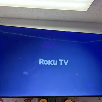 24K CCTV - Mounted 70 inch - A 70-inch flat-screen TV shows the Roku TV logo, mounted on a wall with decorative elements around it. - Security Systems Near Me