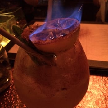 The W - The rum filled fresh lemon garnish on the swizzle as the flame dies down. Lovely and delish! - Cocktail Bars Near Me - Lee's Summit, Missouri