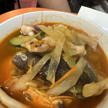 Young Chow Loo - A bowl of spicy seafood soup with vegetables, fish, and broth, served in a restaurant. The soup contains cabbage, zucchini, and seafood pieces. - Korean Near Me - Burlington, Massachusetts