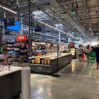 Amazon Fresh - A grocery store interior with customers shopping, checkout counters, and signage for sale and deli sections. - Grocery Near Me - Oceanside, New York