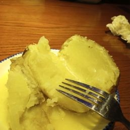 Half baked potato with butter running on the saucer. Half baked potato with butter running on the saucer.