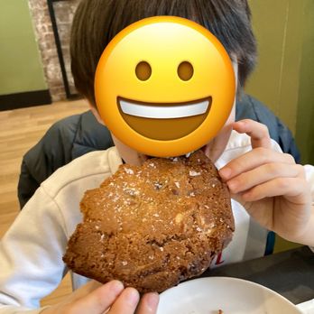 Crossbar - a boy holding a chocolate cookie with a smiley face on it - Coffee & Tea Near Me - New York, New York
