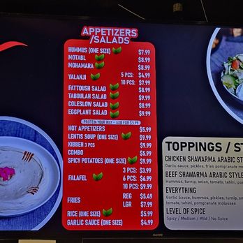 Alpha's Shawarma - Digital menu board at Alpha's Shawarma in Toronto features sections for appetizers, salads, toppings, and styles. It lists items such as hummus, motabl, mohammara, and various salads with prices. The toppings section includes chicken shawarma, beef shawarma, and falafel, with detailed descriptions. The styles section describes different shawarma flavors and sauces. The menu is displayed on a screen with a black background, red accents, and images of food items. - Lebanese Near Me - Toronto, Ontario