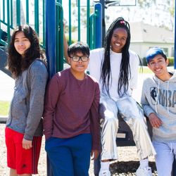 San Diego Center For Children - 4 children sitting on a playground and smiling