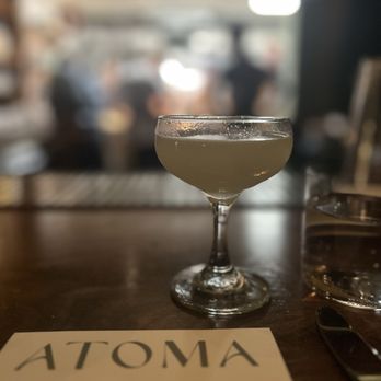 Atoma - Aviator cocktail with Atoma menu and a blur of kitchen activity behind. - New American Near Me - Seattle, Washington Atoma - Aviator cocktail with Atoma menu and a blur of kitchen activity behind. - New American Near Me - Seattle, Washington