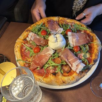 News Café - Pizza News- Tomato sauce, cheese mix, ham, pancetta, salami, prosciutto, rocket and burrata - the signature pizza of the house. - Cafes Near Me - Vienna, 9