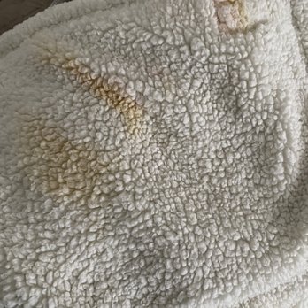 Timeless Cleaners - Stained item returned (not dropped off this way) - A detailed view of a white, textured fabric with a bumpy, plush surface. The fabric has visible stains and discoloration, including brownish spots, indicating it may need cleaning or treatment. - Dry Cleaning Near Me - Lancaster, California