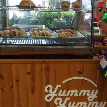 Yummy Yummy Deli - a woman standing in front of a display case of donuts - Latin American Near Me - Miami, Florida Yummy Yummy Deli - a woman standing in front of a display case of donuts - Latin American Near Me - Miami, Florida