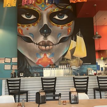 La Zenita - A large mural features a sugar skull face with colorful decorative elements and a ship sailing on water in the background. - Mexican Near Me - Albuquerque, New Mexico