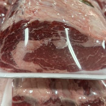 Costco Wholesale - Two trays of raw beef with marbling are shown in a grocery store, wrapped in plastic and stacked on a shelf. - Gas Stations Near Me - Albuquerque, New Mexico
