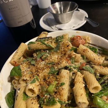 Picone - Pasta - A pasta dish with vegetables and breadcrumbs, accompanied by a bottle of wine and a glass, served at an Italian restaurant. - Italian Near Me - Denton, Texas