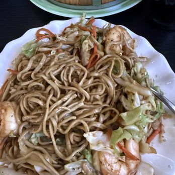 Dumpling Cafe - A white plate holds stir-fried noodles with vegetables like cabbage and carrots, and shrimp, served at a restaurant. - Dim Sum Near Me - Santa Fe, New Mexico