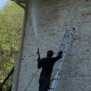 Christian's Lawn Care - a man on a ladder spraying a house - Lawn Services Near Me Christian's Lawn Care - a man on a ladder spraying a house - Lawn Services Near Me