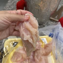 a person holding a piece of raw chicken a person holding a piece of raw chicken