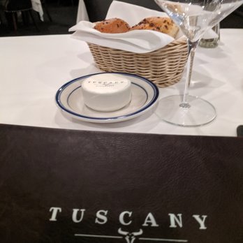 Tuscany - a table setting with a basket of bread and a glass of wine - Italian Near Me - New York, New York