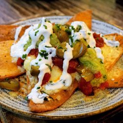 Natural Kitchen - Homemade Nachos: Cajun dusted tortillas, tangy tomato salsa, guacamole, melted mature cheddar, sour cream, jalapenos & fresh chives (£8.50).