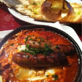 Lola - Merguez lamb sausage over poached eggs in a tomato, onion & pepper concasse - Mediterranean Near Me - Great Neck, New York Lola - Merguez lamb sausage over poached eggs in a tomato, onion & pepper concasse - Mediterranean Near Me - Great Neck, New York