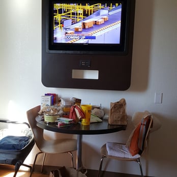 Motel 6 - TV, charging station below, table bolted to wall, uncomfortable wooden chairs.  Suitcase rack  (to the left in this photo). - Hotels Near Me - Gilroy, California