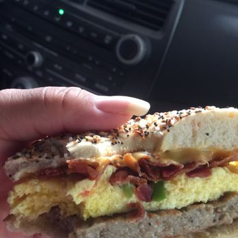 Big Apple Bagels - a person holding a sandwich - Bagels Near Me - Northbrook, Illinois