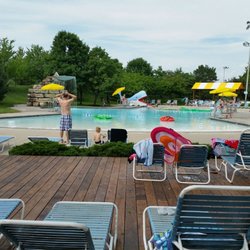 Leawood Aquatic Center - Looking from shaded deck area to pool w/ large floating toys, waterfall feature, zero depth entry, & not deeper than 4ft.