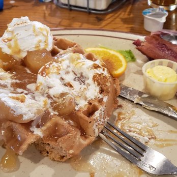 Copper Canyon Cafe - A breakfast plate featuring a waffle with whipped cream, caramel syrup, and cherries, accompanied by bacon, a small dish of butter, and a lemon slice. - Mexican Near Me - Albuquerque, New Mexico