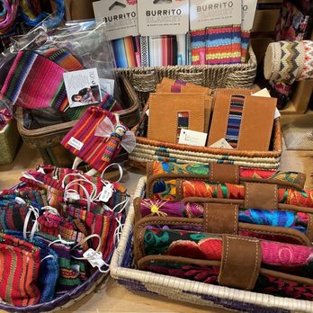 Mestiza - A variety of woven accessories, including scarves, pouches, and blankets, are arranged in baskets and on shelves, showcasing traditional Mexican textile designs. - Jewelry Near Me - Chicago, Illinois