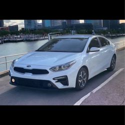 The white Kia Forte with tinted windows offers a sleek look, fuel efficiency, and a comfortable, modern ride.