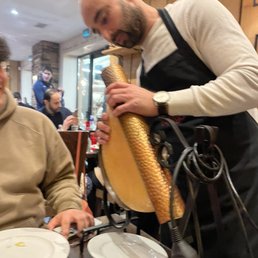 Amir sets up the raclette heater over the giant wheel of cheese.