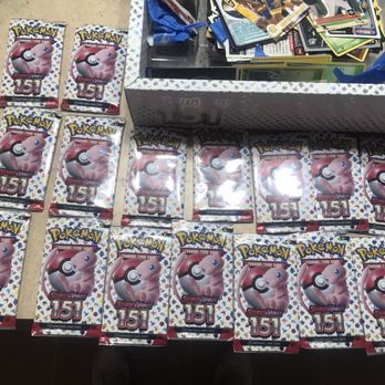 Target - Photo 10 - Several Pokémon Scarlet Violet trading card packs are arranged on a table, with a box of additional cards and loose cards in the background. - Department Stores Near Me - Tucson, Arizona