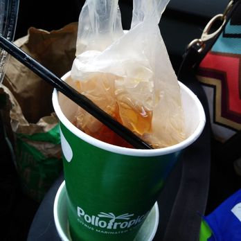 Pollo Tropical - a person holding a bag of food in a cup - Fast Food Near Me - Fort Myers, Florida