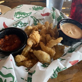 The Tipsy Trout - Calamari - A basket of fried calamari with two dipping sauces, one red and one creamy, on a wooden table with drinks in the background. - American Near Me - Basalt, Colorado