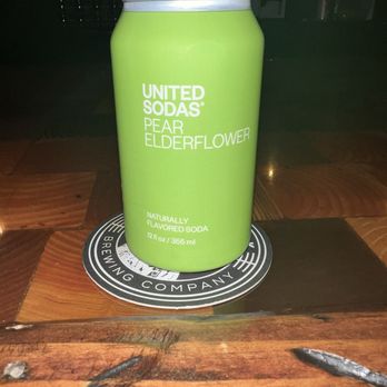 Ghost Hawk Brewing - Non alcoholic option - A 12 oz (365 ml) can of United Sodas Pear Elderflower flavored soda is placed on a circular coaster on a wooden table. - Breweries Near Me - Clifton, New Jersey