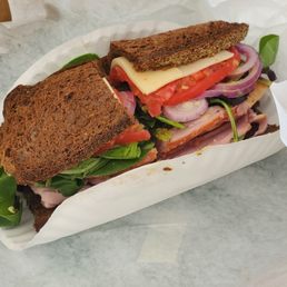 Ham and Swiss Sandwich on Fresh Pumpernickle Bread, with Lettuce, Tomato and Onion and Dijon Mustard.