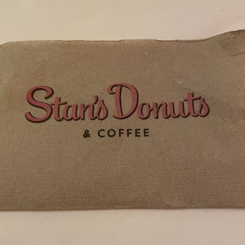 Underground Donut Tour - A brown paper bag features the logo of Star's Donuts & Coffee, with the name 'Star's Donuts' in pink, cursive font and '& Coffee' in black, uppercase letters. The bag is placed on a light-colored surface, and the background is plain and neutral. - Food Tours Near Me - Chicago, Illinois