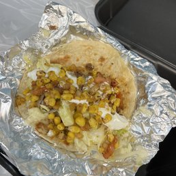 Soft shell beef taco with white American cheese, shredded lettuce, sour cream, and corn salsa