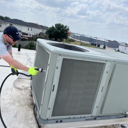 MJS A/C and Heating - The team washing an ac unit on top of a roof as part of maintenance!