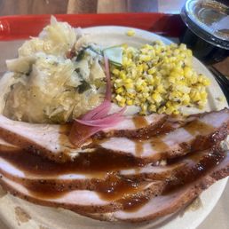Turkey BBQ platter with cabbage and sausage and creamed corn.