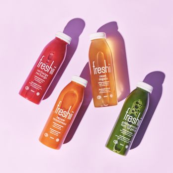 Freshii - three bottles of juice on a pink background - Salad Near Me - Aurora, Ontario Freshii - three bottles of juice on a pink background - Salad Near Me - Aurora, Ontario