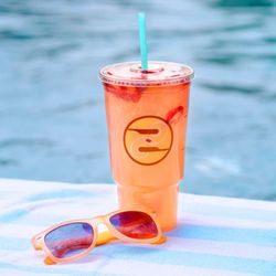 Ziggi's Coffee - Strawberry iced dirty soda in a Ziggi's cup on a towel by the pool with sunglasses.