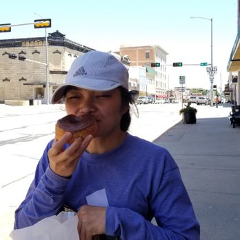 Sunrise Bakery - a woman eating a doughnut on a city street - Bakeries Near Me - Beatrice, Nebraska Sunrise Bakery - a woman eating a doughnut on a city street - Bakeries Near Me - Beatrice, Nebraska
