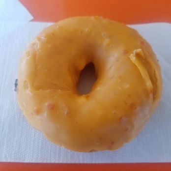 Jax Donuts - Orange Cake donut was citrusy good. - A donut with yellow icing and small bits of nuts or toppings on a white napkin. - Donuts Near Me - Orange, California