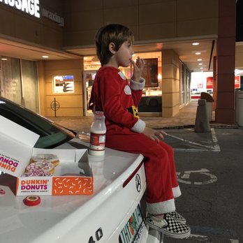 Dunkin' -  a young boy sitting on the hood of a car eating a donut - Donuts Near Me - Miami, Florida