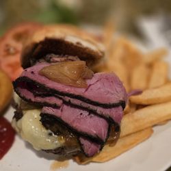 Pastrami-Swiss Cheeseburger with onion rings and steak fries.