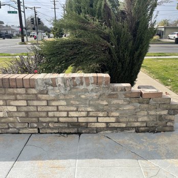 Romero Landscaping - Before photo of the brick wall and bushes to be removed - Landscaping Near Me - San Bernardino, California