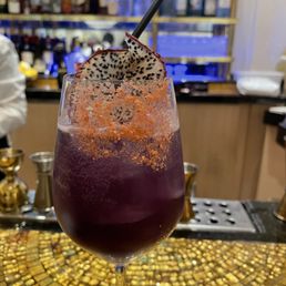 a purple cocktail with a garnish on top