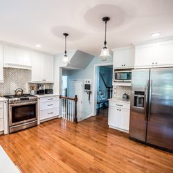 Tile Center - Modern white kitchen with wood floor and natural stone back splash design and installed by Tile Center