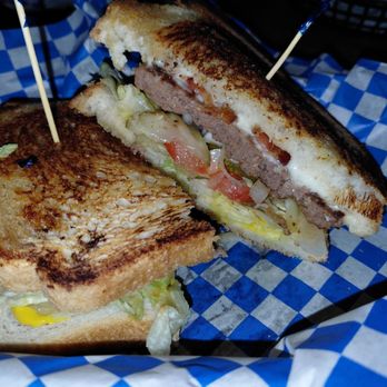 Fast Eddie's MOAB - Sourdough Mo - A grilled cheeseburger with lettuce, tomato, and melted cheese, cut in half, served in a basket with checkered paper. - Fast Food Near Me - Modesto, California