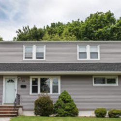 Living Water Home Improvement - Granite gray vinyl siding, new windows with matching cladding, new shingled roof, and updated white 6″ gutters.
