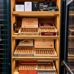 Cali Smokes and Vapes - Wooden cigar display with open boxes beneath a Cali Smokes and Vapes sign.PNG